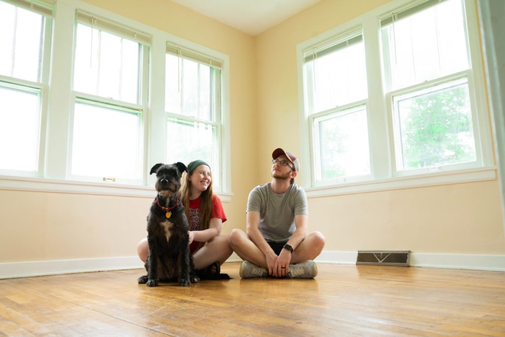 a man and a woman sitting on the floor in a room with windows