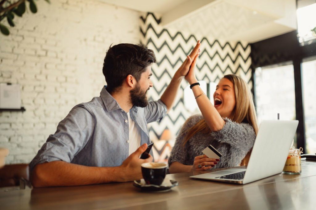 a man and woman sitting at a table with a laptop and a coffee cup