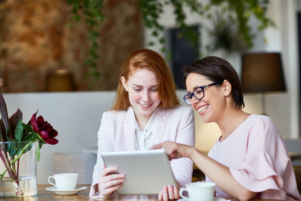 a couple of women sitting at a table with a laptop