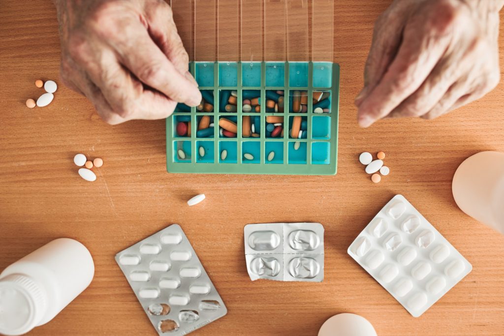 Senior man organizing his medication into pill dispenser. Senior man taking pills from box